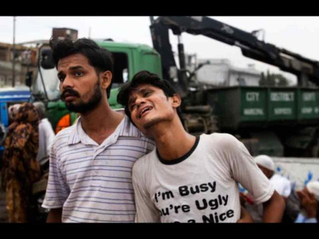 A Pakistani man comforts another who weeps at the site of burnt garment factory in Karachi, Pakistan. Pakistani officials say the death toll from devastating factory fires that broke out in two major cities has risen to 128.(AP/Fareed Khan)