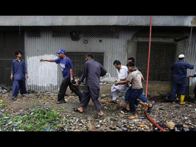 Pakistani rescue workers carry a dead body after recovering from a burnt garment factory in Karachi, Pakistan. A blaze at a shoe factory in the eastern city of Lahore killed 25 people. (AP/Fareed Khan)