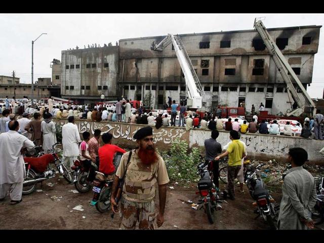 People gather at the site of burnt garment factory in Karachi, Pakistan. (AP/Fareed Khan)