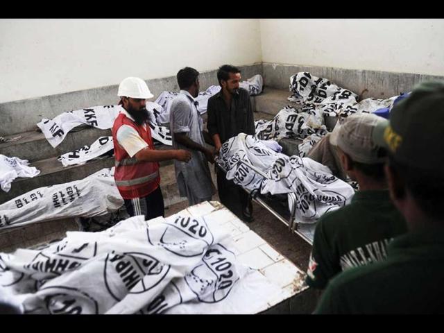 Pakistani policemen and rescuers move the dead body of a garment labourer who was killed after fire erupted at a factory in Karachi. (AFP/Rizwan Tabassum)