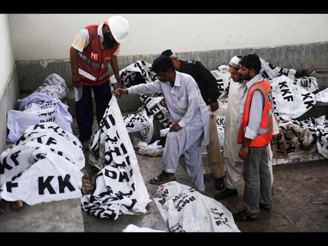 Pakistani policemen and rescuers identify the dead bodies of garment labourers who were killed after fire erupted at a factory in Karachi. (AFP/Rizwan Tabassum)