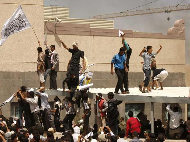 A Yemeni protestor, left, holds a white flag with Islamic inscription in Arabic that reads, "No God but Allah, and Mohammed is his prophet," in front of the US embassy during a protest about a film ridiculing Islam's Prophet Muhammad, in Sanaa, Yemen. Dozens of protesters gather in front of the US Embassy in Sanaa to protest against the American film "The Innocence of Muslims" deemed blasphemous and Islamophobic. (AP Photo/Hani Mohammed)