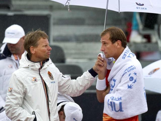 Team coach Jan Siemerink (L) of the Netherlands holds an umbrella for team player Thiemo de Bakker during a rain break in his Davis Cup tennis match against Roger Federer of Switzerland in Amsterdam September 14, 2012. Reuters