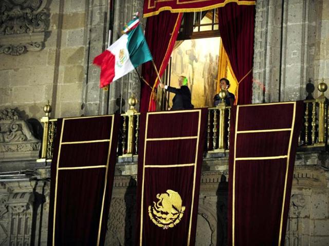 Mexican President Felipe Calderon waves the Mexican national flag beside his wife Margarita Zavala at the start of celebrations for Mexico's Independence Day at the National Palace in Mexico City. AFP/Alfredo Estrella