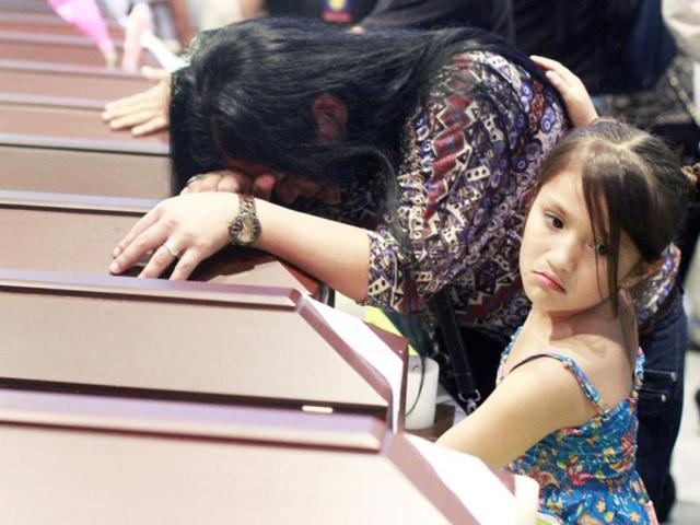 A girl comforts her mother crying on a coffin containing the remains of her relative during a ceremony in Medellin. The prosecutor's office on Tuesday delivered the 17 sets of remains to the families of civilians who were killed two years ago by paramilitary and rebel fighters during the Colombian armed conflict, officials said. Reuters Photo