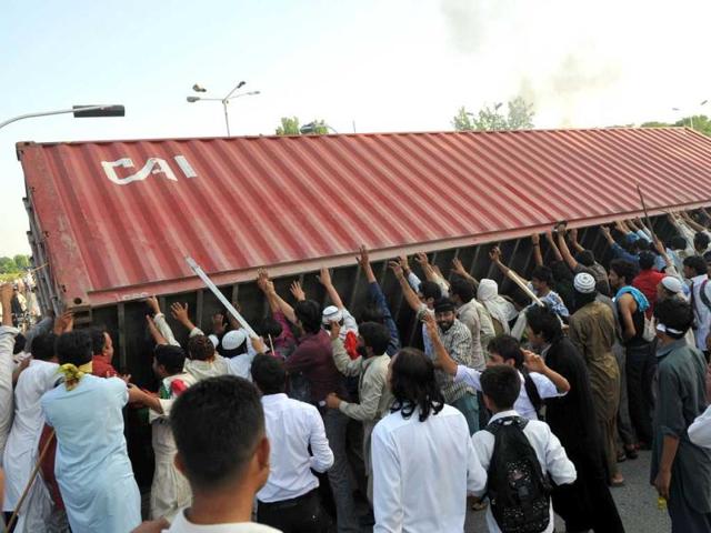 Pakistani demonstrators topple a freight container, placed by police to block a street, as they attempt to reach the US embassy during a protest against an anti-Islam film in Islamabad. AFP/Aamir Qureshi