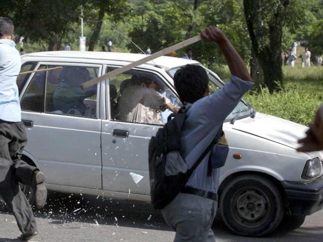 Protesters use sticks to smash the windscreen and windows of a car during an anti-America protest march in Islamabad. Reuters