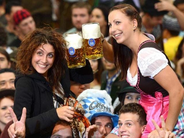 Visitors of the Oktoberfest raise their beers in a festival tent at the start of the Oktoberfest beer festival at the Theresienwiese in Munich, southern Germany. AFP PHOTO / CHRISTOF STACHE