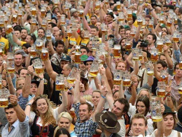 Visitors wearing traditional Bavarian clothes raise their beers in a festival tent at the start of the Oktoberfest beer festival at the Theresienwiese in Munich, southern Germany.. AFP PHOTO / CHRISTOF STACHE