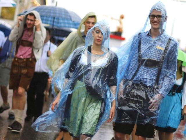 Revellers cover themselves from heavy rain as they stroll over the Munich Oktoberfest at the Theresienwiese in Munich. REUTERS/Kai Pfaffenbach