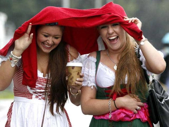 Two women react, as they arrive for the opening of the famous Bavarian "Oktoberfest" beer festival as rain falls, in Munich, southern Germany. (AP Photo/Matthias Schrader)
