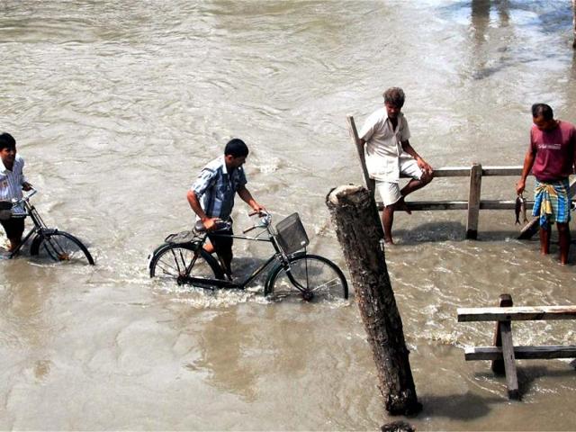 Villagers wades through the flood water at Kanikuch under Kamrup district in Assam. PTI Photo