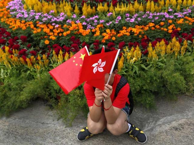 A boy from mainland China poses with a Chinese national flag, left, and a Hong Kong flag at the venue of a flag-raising ceremony celebrating China's National Day in Hong Kong. AP Photo