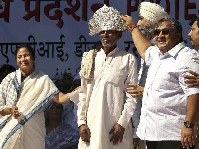Trinamool Congress party leader Mamata Banerjee presents a crown to a farmer that was presented to her by supporters at a rally in New Delhi. (AP Photo/Saurabh Das)