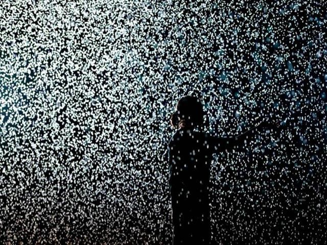A woman poses for pictures in an art installation entitled "Rain Room" during a photocall at the Barbican in London. The 'Rain Room', a 100 square meter field of falling water invites visitors to walk into. As the visitor walks through the rain stops around them, giving them an experience of how it might feel to control the rain. AFP/Leon Neal