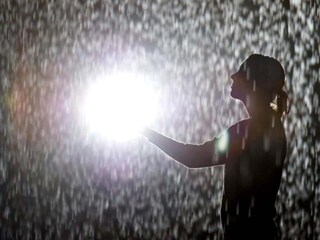 A woman poses for pictures in an art installation entitled "Rain Room" during a photocall at the Barbican in London. AFP/Leon Neal
