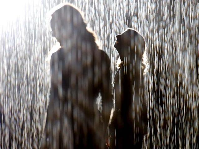 Visitors walk through an art installation entitled "Rain Room" during a photocall at the Barbican in London. AFP/Leon Neal