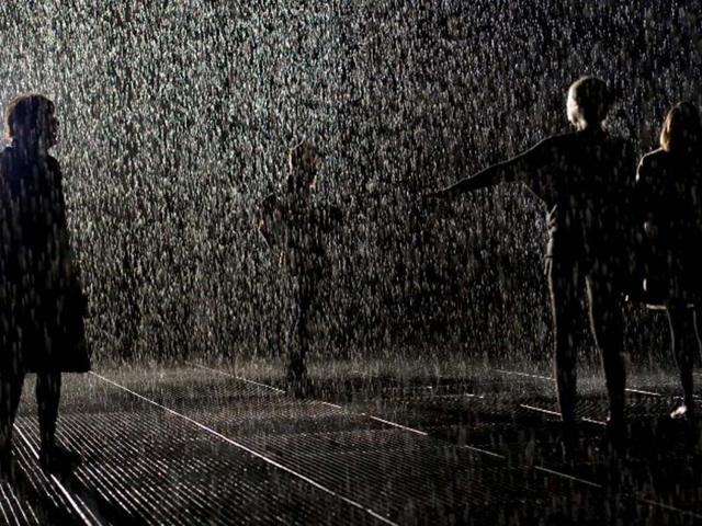 Visitors walk through an art installation entitled "Rain Room" during a photocall at the Barbican in London. AFP/Leon Neal