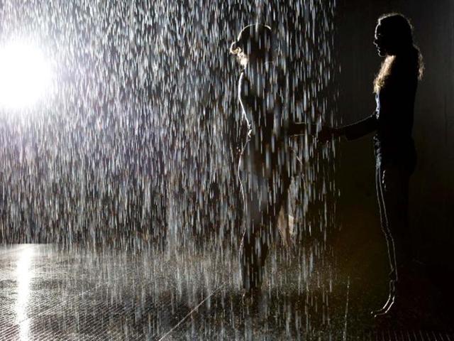 Two women shake hands as they pose for pictures in an art installation entitled "Rain Room" during a photocall at the Barbican in London. AFP/Leon Neal