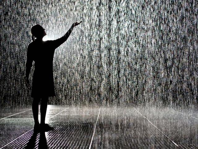 A woman poses for pictures in an art installation entitled "Rain Room" during a photocall at the Barbican in London. AFP/Leon Neal