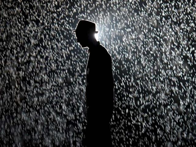 A man poses for pictures as he walks through an art installation entitled "Rain Room" during a photocall at the Barbican in London. AFP/Leon Neal