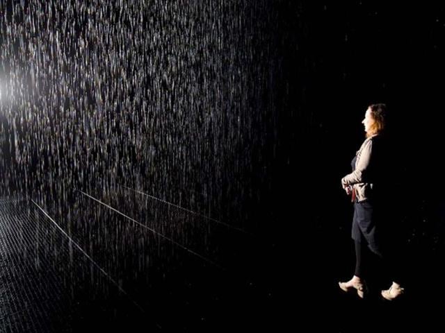 A woman walks through an art installation entitled "Rain Room" during a photocall at the Barbican in London. AFP/Leon Neal