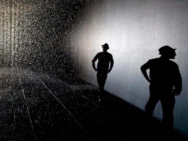 A man poses for pictures at an art installation entitled "Rain Room" during a photocall at the Barbican in London. AFP/Leon Neal