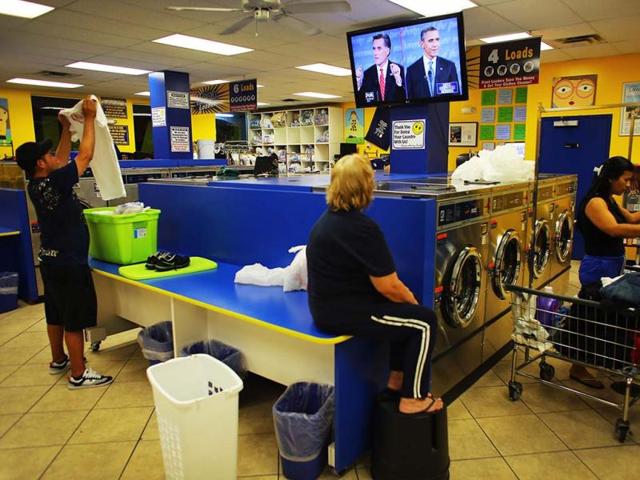 People at the Lavanderia coin laundry watch as US President Barack Obama and Republican presidential candidate and former Massachusetts Governor Mitt Romney are seen during their televised debate in Miami, Florida. (AFP Photo)