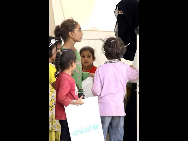 Young Syrian refugees talk to their teacher at a UNICEF-run school in the al-Zaatari refugee camp in the Jordanian city of Mafraq near the border with Syria. The school is a grant from the European Union to provide education to Syrian refugees residing in Jordan. AFP/Khalil Mazraawi