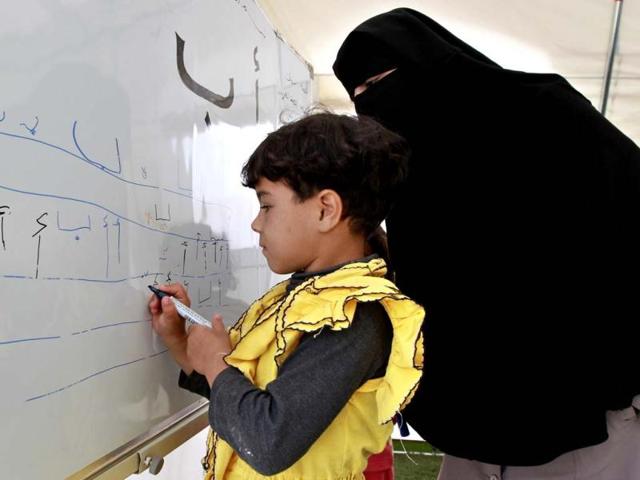 A Syrian child refugee writes on a whiteboard during her fourth day of school at Al Zaatri refugee camp, in the Jordanian city of Mafraq, near the border with Syria. The school is a grant from the European Union to provide education to Syrian refugees residing in Jordan. Reuters/Muhammad Hamed