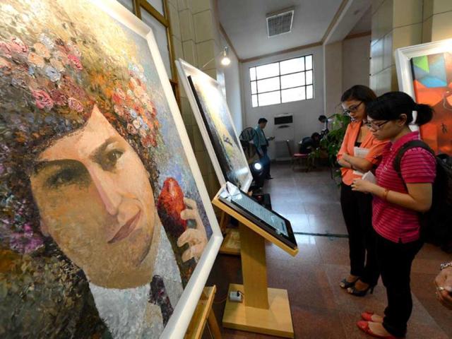 People-attend-the-opening-ceremony-of-an-art-exhibition-in-commemoration-of-the-late-Apple-s-co-founder-Steve-Jobs-on-the-occasion-of-his-first-death-anniversary-in-Hanoi-AFP-Photo-Hoang-Dinh-Nam