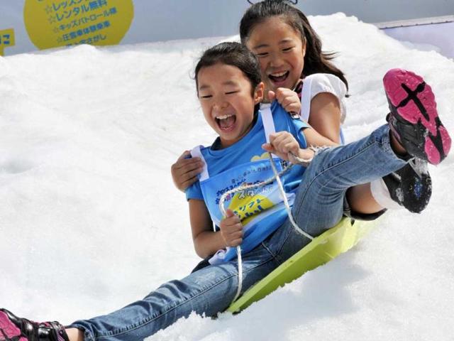 Young girls ride a sledge on a snow slope at a hotel in Tokyo. The hotel carried 25 tons of artificial snow from their Naeba ski resort on the first day of three consecutive autumn holidays for the promotion of the ski resort. (AFP photo/Yoshikazu Tsuno)