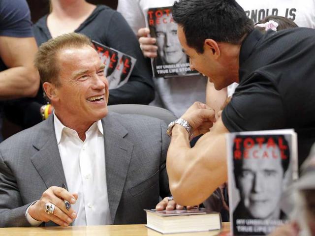 A man flexes his muscles for former California Governor Arnold Schwarzenegger during a book signing event for his book "Total Recall," at a Barnes Noble store in Los Angeles. (AP Photo/Jae C. Hong)