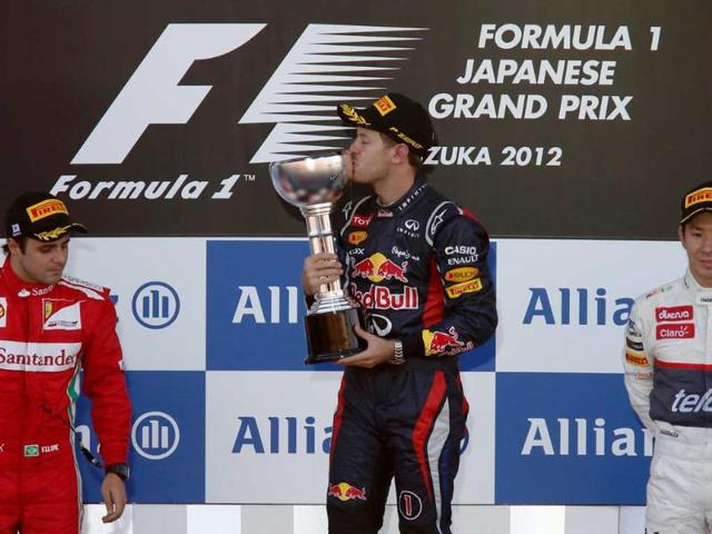 Red Bull Formula One driver Sebastian Vettel of Germany (C) kisses his trophy on podium next to second placed Ferrari Formula One driver Felipe Massa of Brazil (L) and thrid placed Sauber Formula One driver Kamui Kobayashi of Japan after the Japanese F1 Grand Prix at the Suzuka circuit. (Reuters/Kim Kyung-Hoon) 