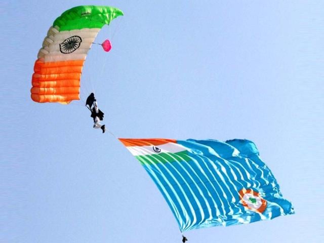 An IAF person carries the force's flag as he descends with a parachute during 80th Air Force Day celebrations at Air Force Station in Hindon. PTI Photo