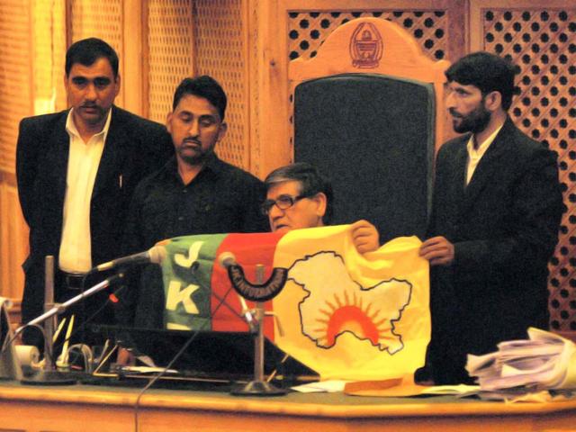 Speaker Mohammad Akbar Lone displays the flag that was carried by an intruder in Jammu and Kashmir assembly in Srinagar. PTI