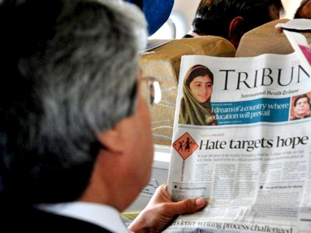 A Pakistani passenger reads a local newspaper featuring news of Malala Yousafzai during a flight over Pakistan, a day after Yousafzai was shot in the head in an assassination attempt. AFP /Farooq Naeem