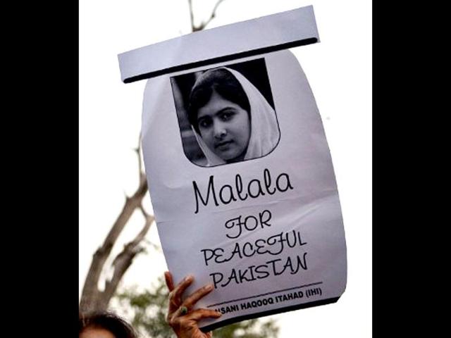 A Pakistani civil society activist carries a placard with a photograph of gunshot victim Malala Yousafzai as they shout ant-Taliban slogans during a protest rally against the assassination attempt on Malala Yousafzai, in Islamabad. AFP / Aamir Qureshi