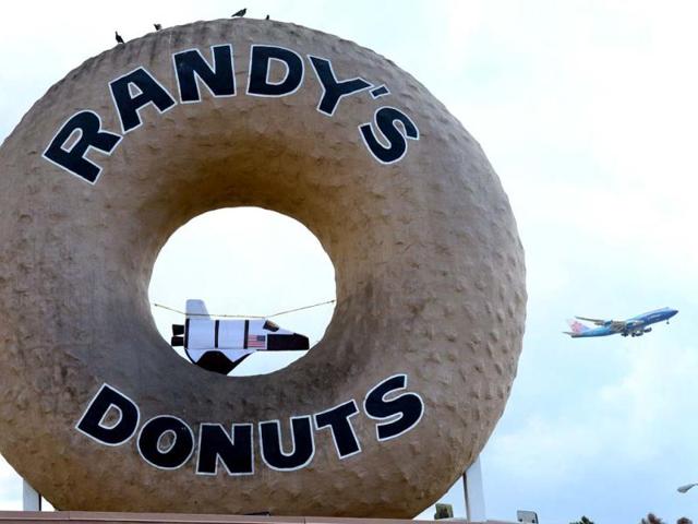 An airplane passes the giant donut on the roof of Randy's Donuts where a mini US Space Shuttle is strung up in the donut hole in Inglewood, in southwest Los Angeles County, California, along the route the US Space Shuttle Endeavour will pass in coming days. AFP photo