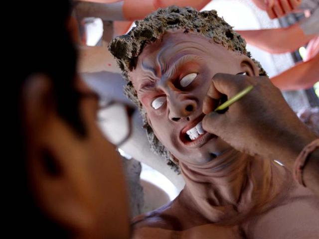 An artist paints the idol of the demon Mahishasur for the Durga puja festival in Chittaranjan Park in New Delhi. HT photo/Arijit Sen