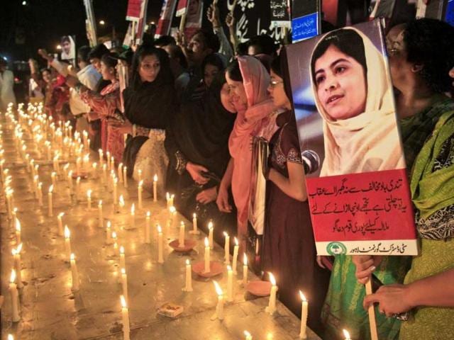 A Pakistani woman holds a poster of 14-year-old schoolgirl Malala Yousufzai, who was shot by the Taliban for speaking out in support of education for women, during a candlelight vigil in Lahore, Pakistan. AP/KM Chaudary