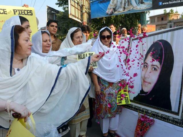 Pakistani women shower rose petals on a photograph of child activist Malala Yousafzai, who was shot in the head in a Taliban assassination attempt, as they pay tribute in Peshawar. AFP Photo/A.Majeed