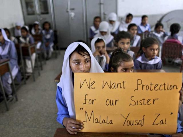 Pakistani girls display a poster while sitting at their desk, as their teacher, not shown, talks to them about 14-year-old schoolgirl Malala Yousufzai, who was shot by a Taliban gunman for her role in promoting girls' education in the Swat Valley where she lives, in a school in Islamabad. AP Photo/Muhammed Muheisen
