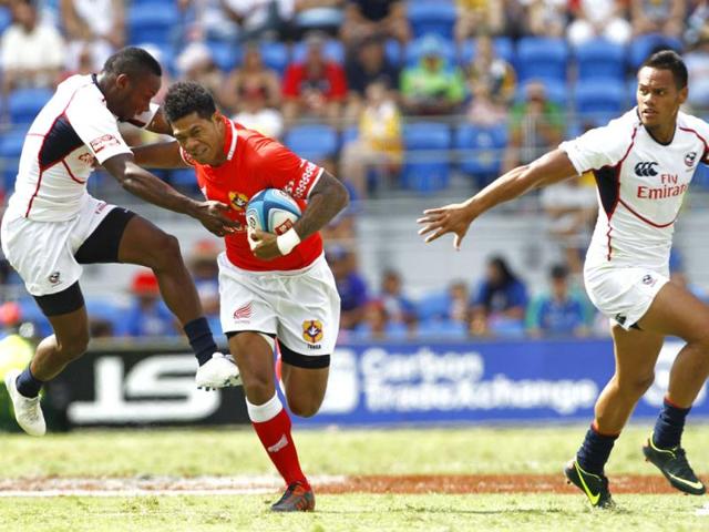 Tonga player Kilifi Latua palms off the tackle of US player Tai Enosa as Maka Unufe looks on during their match at the IRB Sevens rugby tournament at Skilled Park in Gold Coast. AFP/Patrick Hamilton