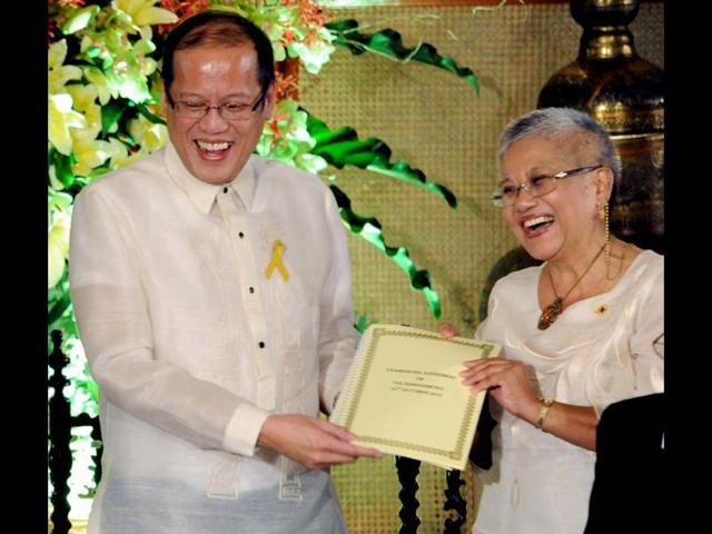 Philippine President Benigno Aquino and Government peace negotiator Teresita Deles, smile as they hold a signed document of the frame works of agreement for peace at Malacanang Palace in Manila. AFP/Jay Directo