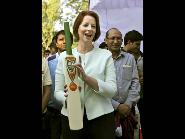 Australia's Prime Minister Julia Gillard holds a bat after joking about how she would not play in front of the cameras, at a camp for underprivileged children in New Delhi. Gillard is on a three day official visit to India. (AP Photo)