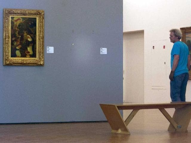 A man pauses to look at the empty space where Henri Matisse' painting "La Liseuse en Blanc et Jaune" was hanging, right, next to a painting by Maurice Denis, left, at Kunsthal museum in Rotterdam, Netherlands. Seven paintings by artists including Pablo Picasso and Claude Monet were stolen from a museum in Rotterdam in an early-hours heist, Dutch police said. (AP Photo/Peter Dejong)