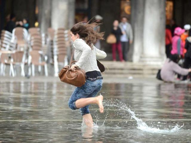A woman runs in water on a flooded St Mark's square during the first "acqua alta" of the season in Venice. The "acqua alta", a convergence of high tides and a strong sirocco, reached 105 centimeters. AFP photo