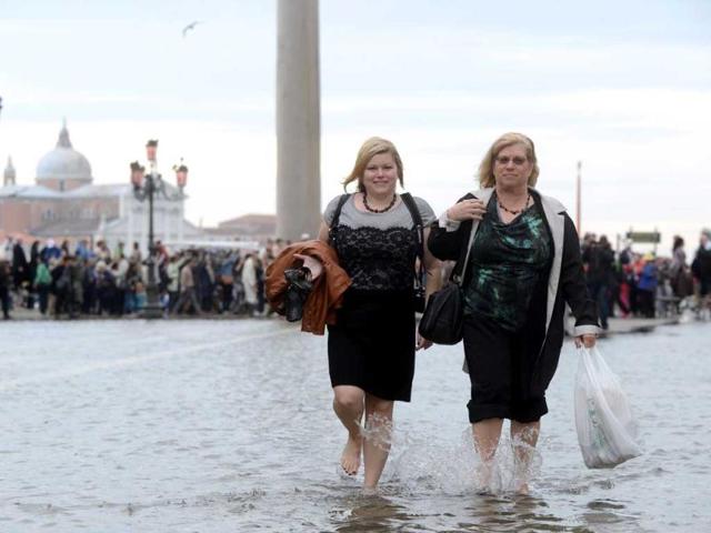 Tourists walk barefoot on a flooded St Mark's square during the first "acqua alta" of the season in Venice. The "acqua alta", a convergence of high tides and a strong sirocco, reached 105 centimeters. AFP photo