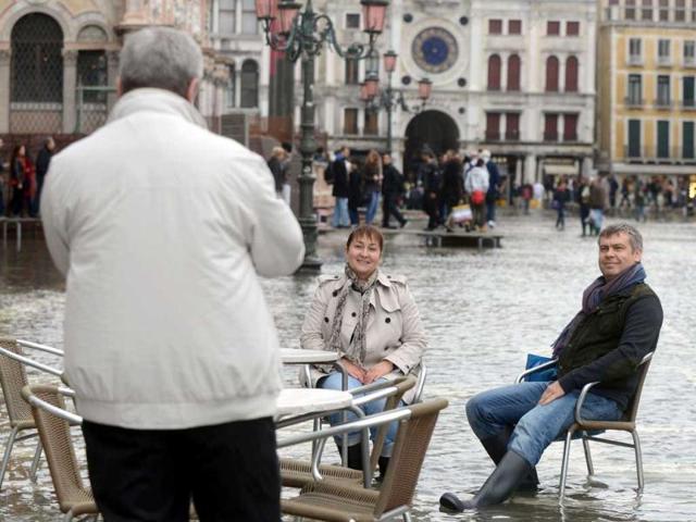 Tourist seat a cafe terrace on a flooded St Mark's square during the first "acqua alta" of the season in Venice. The "acqua alta", a convergence of high tides and a strong sirocco, reached 105 centimeters. AFP photo